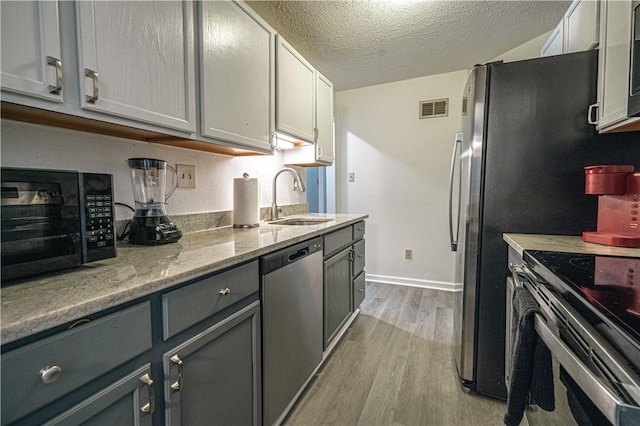 kitchen with sink, gray cabinets, light wood-type flooring, and appliances with stainless steel finishes