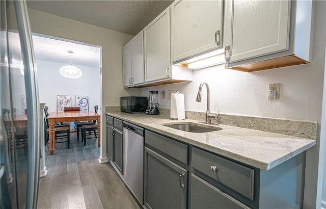 kitchen featuring pendant lighting, dishwasher, wood-type flooring, sink, and gray cabinetry