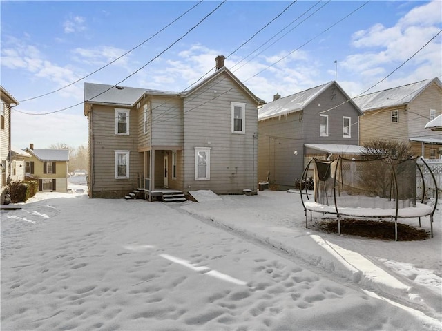 snow covered back of property featuring a trampoline