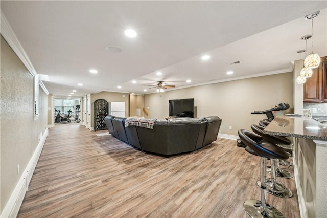 living room featuring crown molding, light hardwood / wood-style floors, and ceiling fan