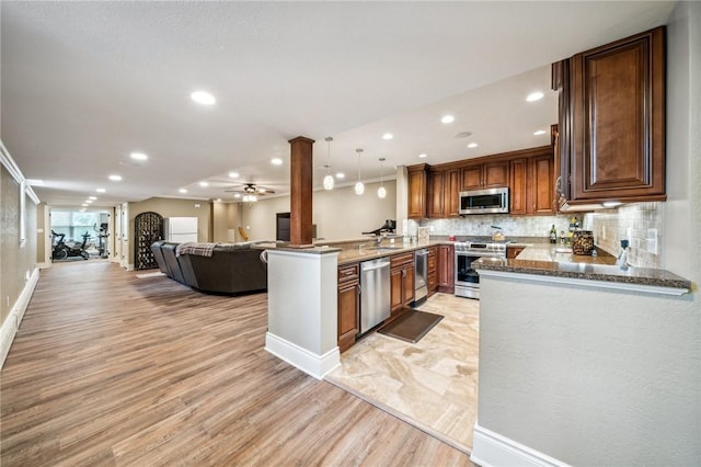 kitchen with kitchen peninsula, crown molding, pendant lighting, ornate columns, and stainless steel appliances