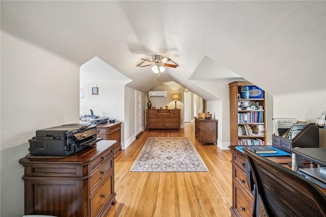 bedroom featuring light hardwood / wood-style floors, a wall unit AC, and vaulted ceiling