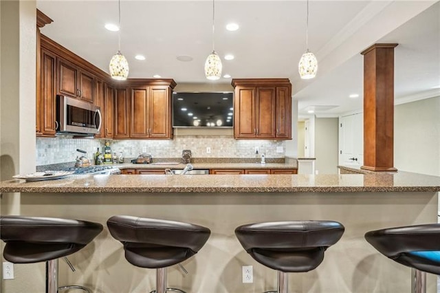 kitchen with decorative light fixtures, a kitchen bar, and light stone countertops