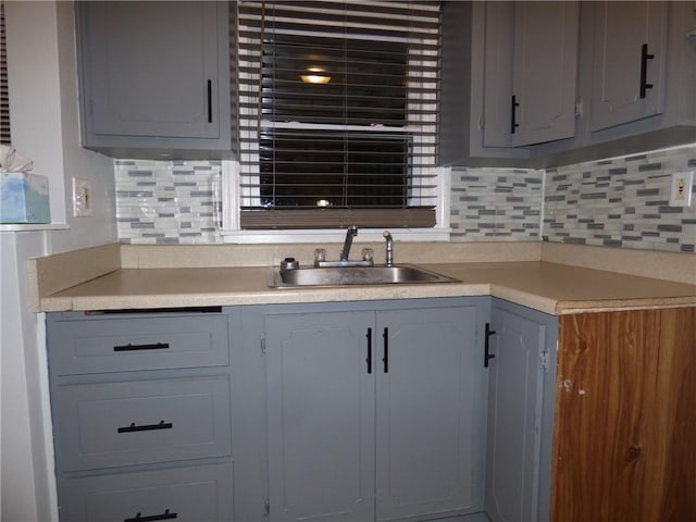 kitchen with backsplash, sink, and gray cabinetry