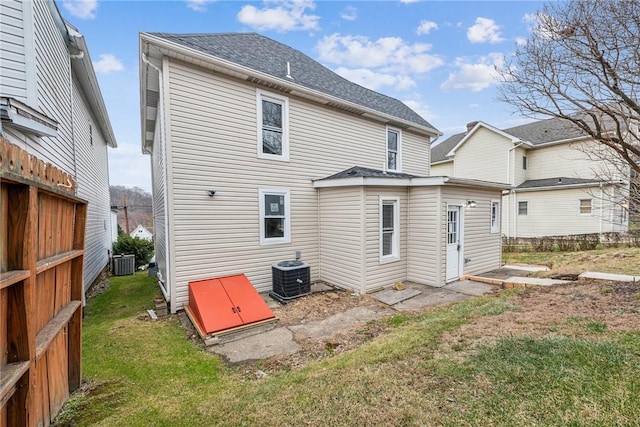 back of house with cooling unit and a yard