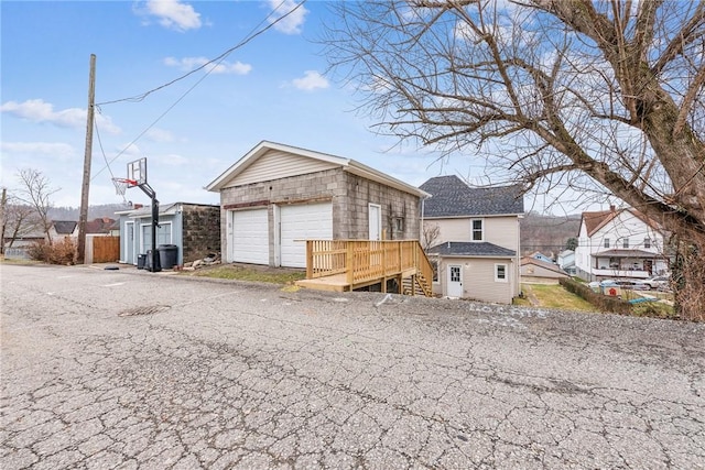 view of front of property with a wooden deck, an outbuilding, and a garage