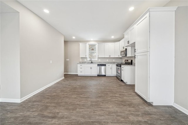 kitchen featuring white cabinets, stainless steel appliances, sink, dark hardwood / wood-style floors, and light stone counters