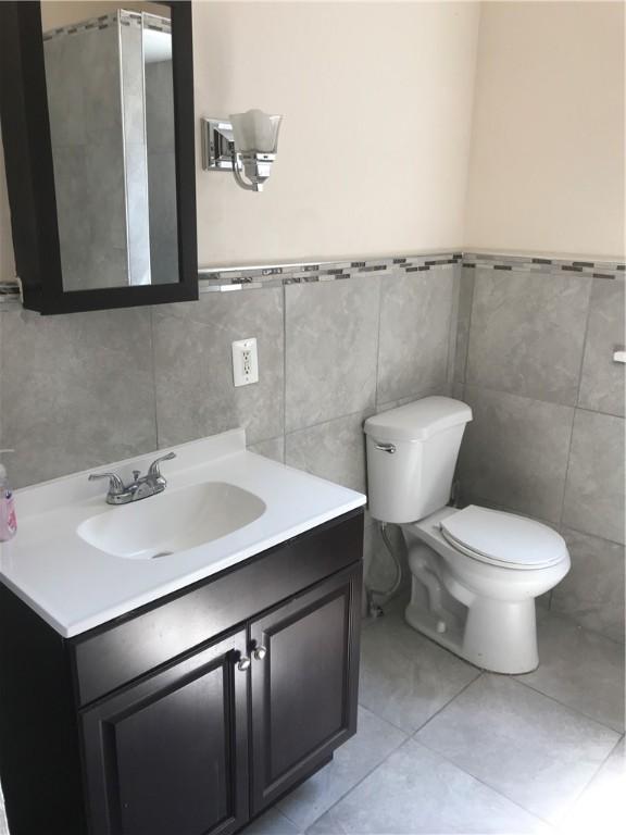 bathroom with vanity, toilet, tile patterned floors, and tile walls