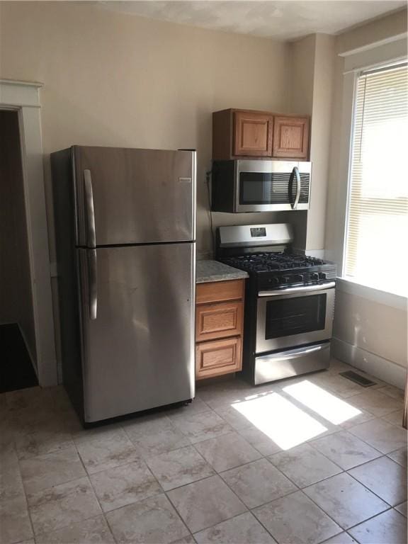 kitchen featuring light stone counters, light tile patterned floors, and appliances with stainless steel finishes