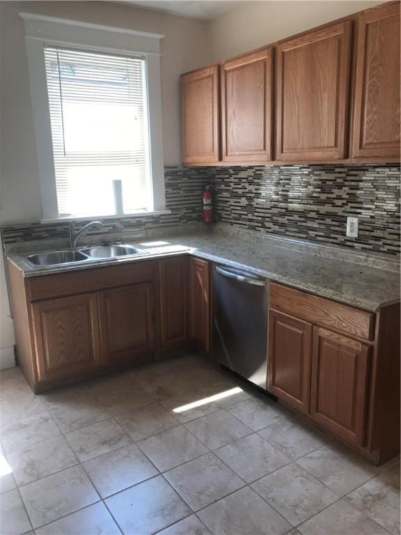 kitchen featuring stainless steel dishwasher, sink, light tile patterned floors, light stone countertops, and decorative backsplash