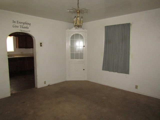 unfurnished room featuring a chandelier