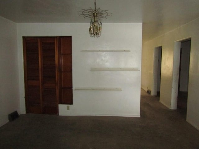 spare room with a chandelier and carpet flooring