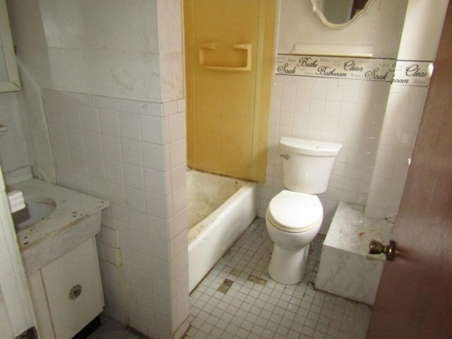 bathroom with toilet, vanity, tile patterned floors, and tile walls