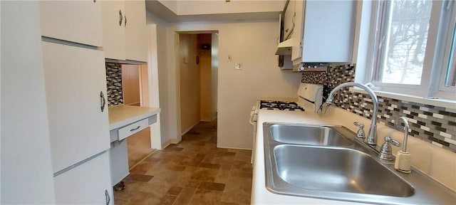 kitchen with white cabinets, white gas stove, decorative backsplash, and sink