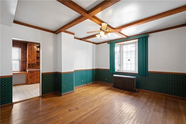 empty room featuring ceiling fan, radiator, beam ceiling, hardwood / wood-style floors, and coffered ceiling