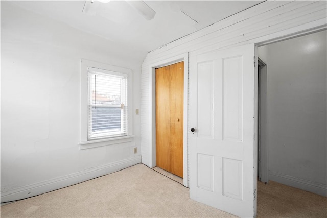 unfurnished bedroom featuring ceiling fan, light colored carpet, and vaulted ceiling