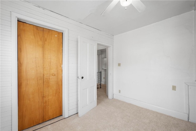 unfurnished bedroom featuring light colored carpet, a closet, and ceiling fan