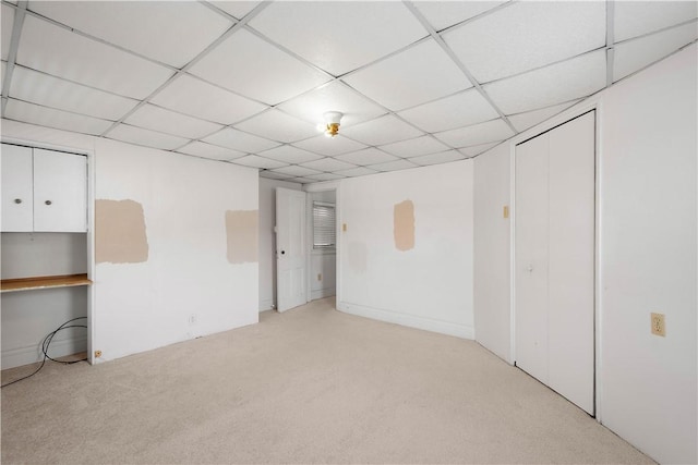 basement featuring light colored carpet and a drop ceiling