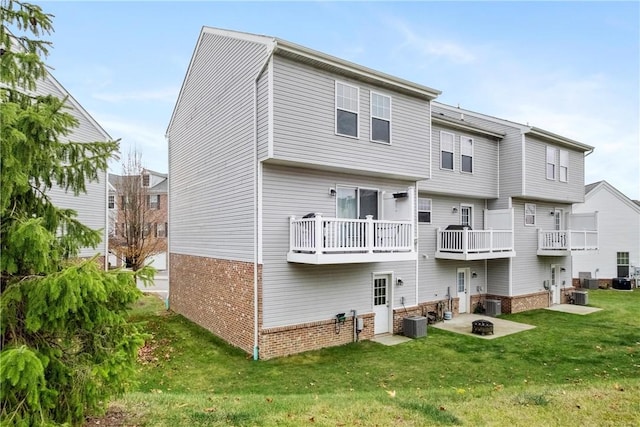 back of property featuring a balcony, a lawn, and central air condition unit