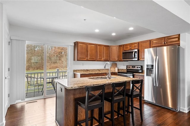 kitchen featuring light stone countertops, a kitchen island with sink, sink, stainless steel appliances, and plenty of natural light