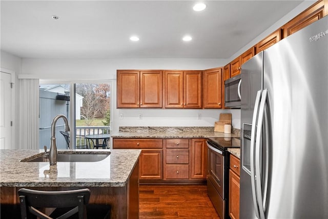 kitchen with sink, dark hardwood / wood-style flooring, light stone countertops, and appliances with stainless steel finishes