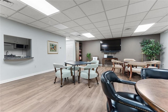 dining area with light hardwood / wood-style floors and a paneled ceiling