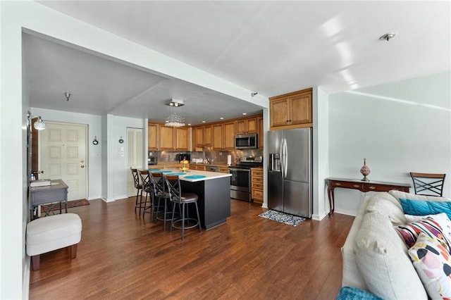 kitchen with a center island, stainless steel appliances, tasteful backsplash, a kitchen breakfast bar, and dark hardwood / wood-style floors