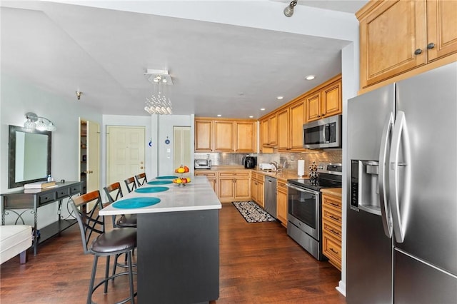 kitchen featuring a kitchen island, stainless steel appliances, a kitchen breakfast bar, backsplash, and hanging light fixtures