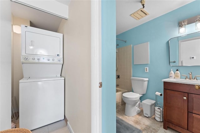 full bathroom featuring toilet, stacked washer and clothes dryer, tiled shower / bath, and vanity