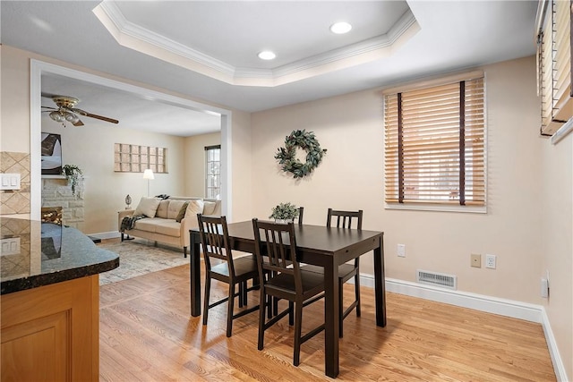 dining area featuring crown molding, light hardwood / wood-style flooring, a wealth of natural light, and a tray ceiling