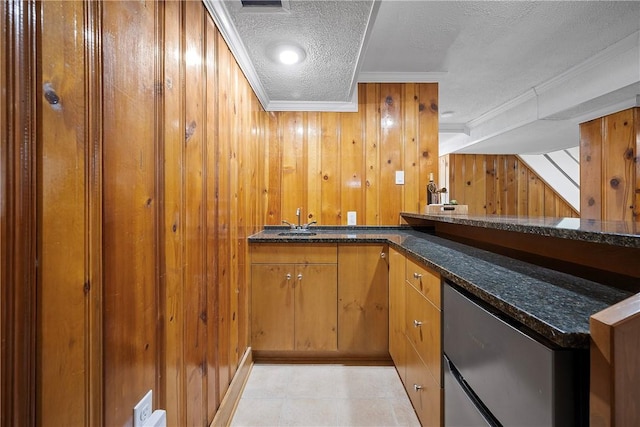 bar featuring ornamental molding, dark stone counters, wooden walls, and a textured ceiling