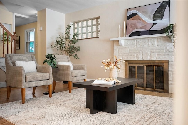 sitting room featuring a stone fireplace and wood-type flooring