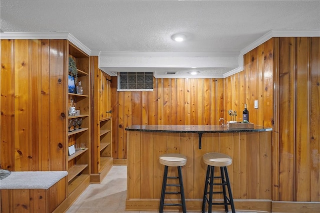 bar with ornamental molding, wooden walls, and a textured ceiling