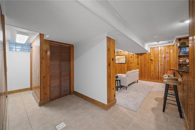 hallway with crown molding, wood walls, and a textured ceiling