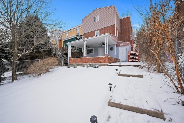 snow covered rear of property featuring a porch and ceiling fan