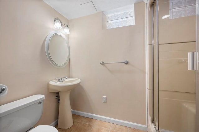 bathroom featuring a shower with shower door, toilet, and tile patterned flooring