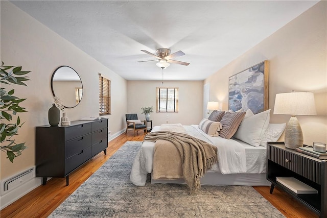 bedroom featuring ceiling fan, baseboard heating, and wood-type flooring