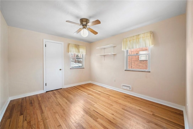 spare room featuring light wood-type flooring, ceiling fan, and plenty of natural light