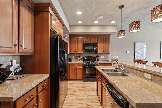 kitchen featuring black appliances, hanging light fixtures, a center island with sink, and sink