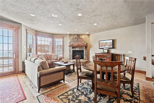 living room featuring a fireplace, light hardwood / wood-style flooring, and a textured ceiling