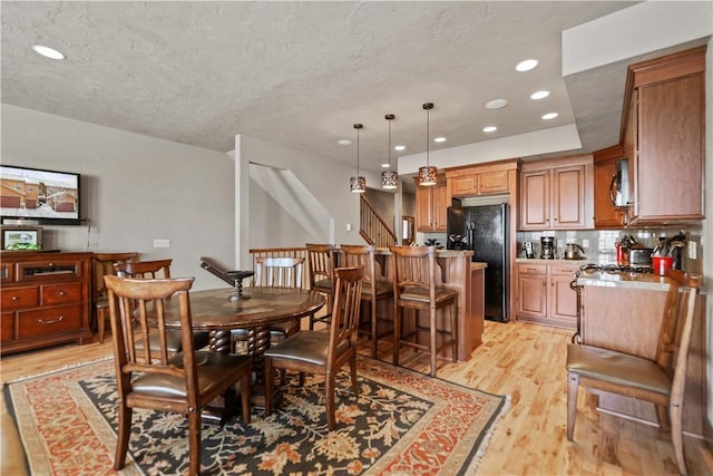 dining space featuring light wood-type flooring and a textured ceiling