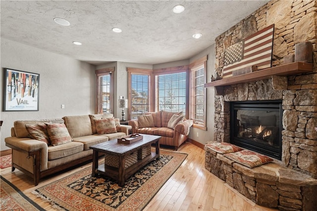 living room with a fireplace, light hardwood / wood-style floors, and a textured ceiling