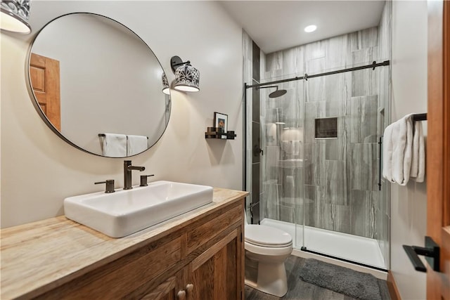 bathroom with a shower with shower door, toilet, and vanity