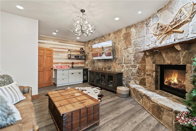 living room with a fireplace, hardwood / wood-style floors, sink, and a chandelier