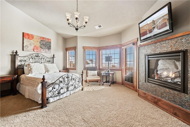 carpeted bedroom with vaulted ceiling, a chandelier, and a tiled fireplace