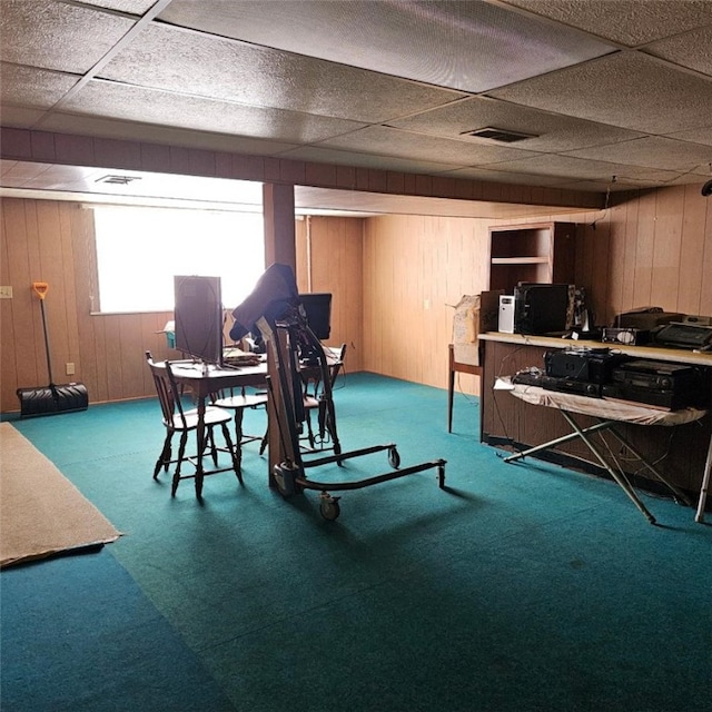 dining area with carpet, wood walls, and a paneled ceiling