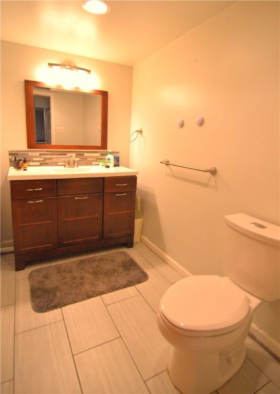 bathroom featuring tasteful backsplash, vanity, and toilet