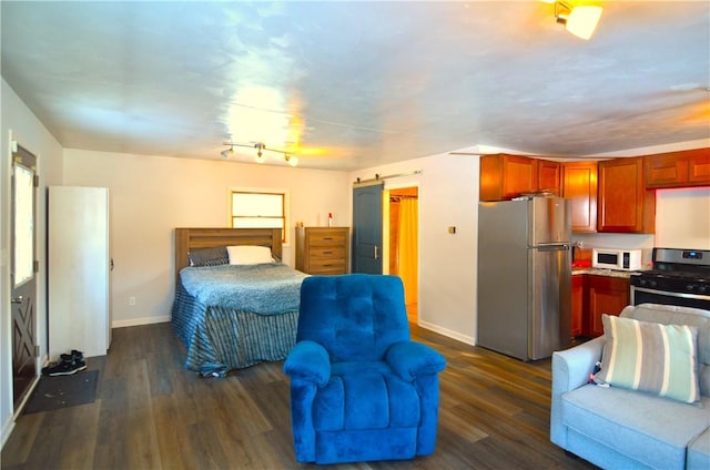 bedroom with a barn door, dark hardwood / wood-style floors, and stainless steel refrigerator