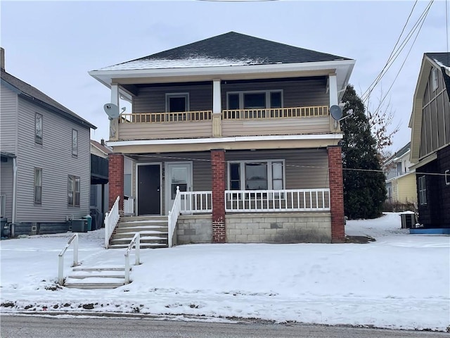 view of front property featuring a balcony, a porch, and central AC