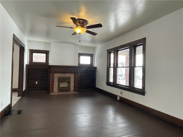 unfurnished living room featuring a tile fireplace, dark wood-type flooring, and ceiling fan